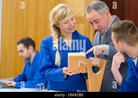 teacher helping a students in a woodwork class Stock Photo