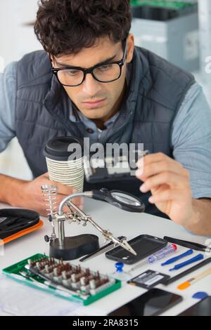 young energetic male tech or engineer repairs electronic equipment Stock Photo