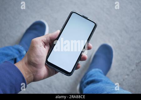 pov shot of young man hand using smart phone with white screen while sitting  Stock Photo