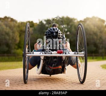 Disability, bicycle and paraplegic person cycling as morning exercise, workout or training for wellness and health. Handbike, sports and person on a Stock Photo