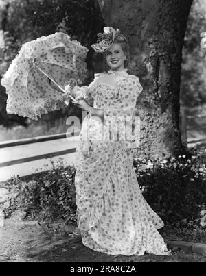 United States:  c. 1940 An attractive young woman in Victorian dress holding a parasol. Stock Photo