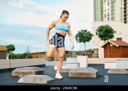 Muscular woman doing workout on sports ground, stretching leg Stock Photo