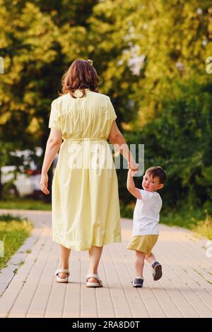 Child feels a mix of emotions as he looks back at his mom, unsure of what the future holds. The unhappy baby clings to his mother's hand, hoping that Stock Photo