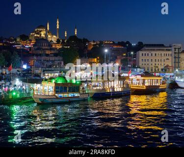 Fish sandwich (Balık ekmek) boats on the Golden Horn River in Eminonu, neighbourhood with the Suleymaniye Mosque on the hill behind, Istanbul, Turkey. Stock Photo