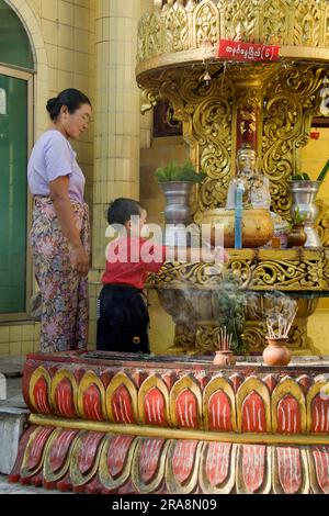 Child pours holy water on Buddha, Sule Pagoda, Yangon, Burma, Myanmar, Rangoon Stock Photo