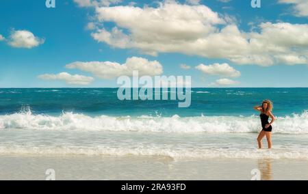 on a sunny day woman stands on the beach  in a posing postion Stock Photo