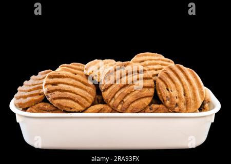 Side View Of A Stack Of Delicious Chocolate Chip Cookies In White Square Bowl on a Black Surface Stock Photo