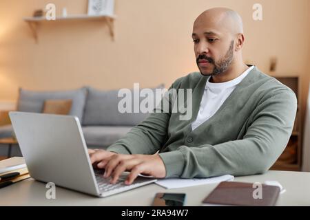 Portrait of adult black man using laptop while working from home in cozy setting, copy space Stock Photo
