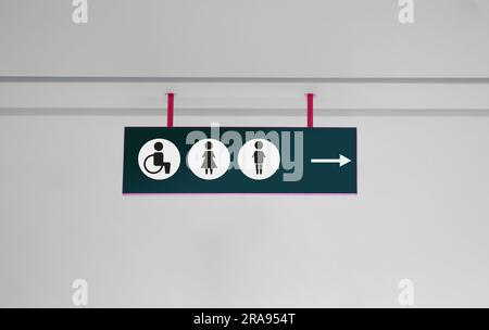 Public toilet sign with symbols and arrow showing direction Stock Photo