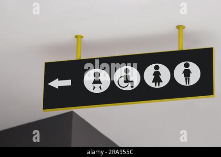 Public toilet sign with symbols and arrow showing direction Stock Photo