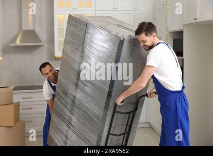 Male movers carrying refrigerator in new house Stock Photo