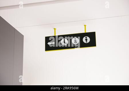 Public toilet sign with symbols and arrow showing direction Stock Photo