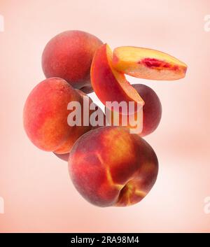 Cut and whole fresh ripe peaches falling on pink background Stock Photo