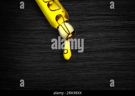 Dripping cosmetic oil from pipette onto brunette hair, closeup Stock Photo