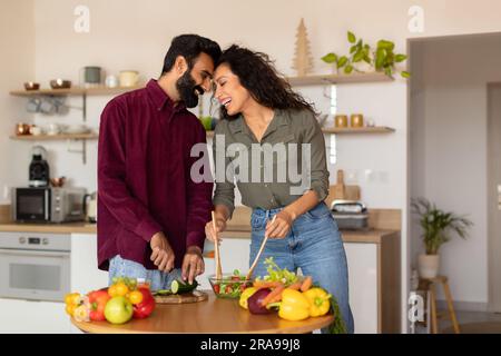 Romantic arab spouses bonding, preparing meal together, loving husband and wife cooking, kitchen interior, copy space Stock Photo