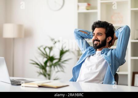 Relaxed Indian Male Freelancer Leaning Back In Chair, Resting After Online Work Stock Photo