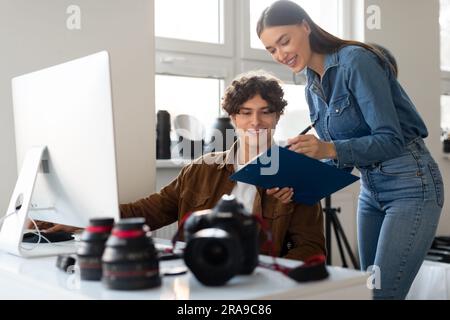 Photographer and his assistant working together with computer, planning photoshoot or selecting photos after shooting Stock Photo