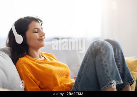 Relaxed peaceful eastern woman listening to music at home Stock Photo