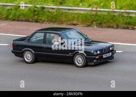 1998 80s eighties BMW 325I Se Black Car Saloon Petrol 2494 cc; travelling at speed on the M6 motorway in Greater Manchester, UK Stock Photo