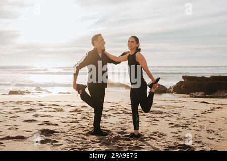 Laughing senior caucasian couple in sportswear doing legs stretching, practicing yoga, enjoy workout Stock Photo
