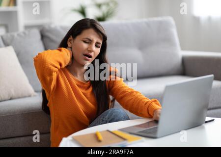 Tired young indian woman freelancer suffering from neck pain Stock Photo