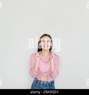 Thrilled young pretty woman clenching fists and looking up Stock Photo