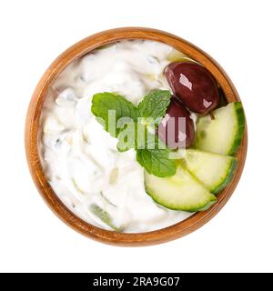 Tzatziki, Greek dip sauce in a wooden bowl. Appetizer and side dish made of strained yogurt, mixed with cucumber, garlic, salt, olive oil, and garnish. Stock Photo