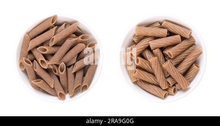 Buckwheat penne and tortiglioni, gluten free whole grain pasta, in white bowls. Brown noodles, made of pure buckwheat semolina, extruded into cylinder. Stock Photo