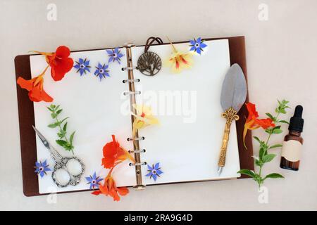Cold and flu remedy essential oil preparation with borage, nasturtium and lemon balm herbs and flowers with old leather notebook. Stock Photo