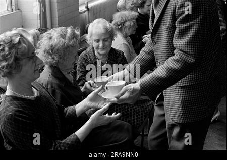 Cup of tea at a Darby and Joan Club. A blind and partially sighted afternoon dance class for senior citizens at the Battersea Institute. Cups of tea are handed around by the more able members of the class at the end of the session. Battersea, London, England circa 1970. 1970s UK HOMER SYKES Stock Photo