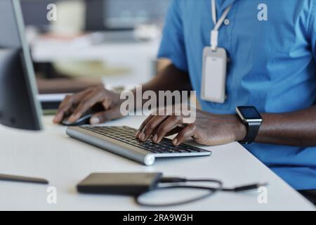 Focus on left hand of young African American male software developer touching keys of computer keyboard while working over new project Stock Photo