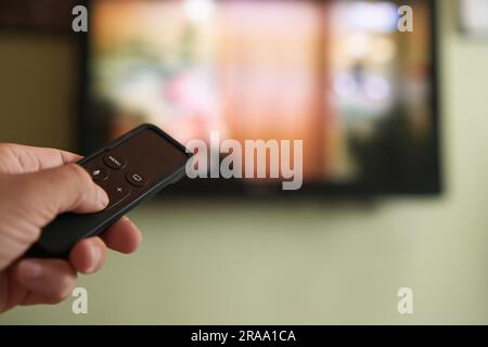 Multimedia streaming concept. Hand holding remote control. TV screen with lot of pictures. Stock Photo