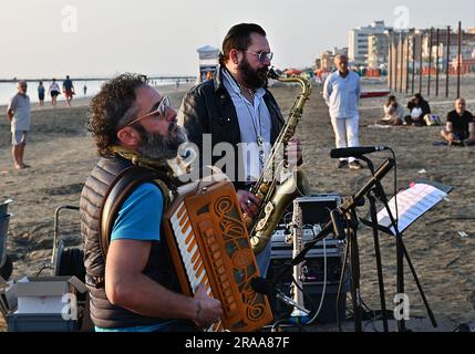 Sunrise concerts (6 a.m.) with Simone Zanchini accordion and Stefano Bedetti on saxes. Free beach of Villamarina of Cesenatico, Adriatic coast, italy. Stock Photo