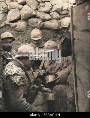 Dinner-time for soldiers in a corner of a fire-trench on the French front in the Argonne. The caption reads: 'The clockwork regularity of the French culinary arrangements at the front, and the food-supply system to the troops in the battlefield region, have been repeatedly remarked on as a wonder of French war organisation'.     Date: 1917 Stock Photo