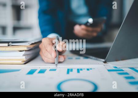 businessman or accountant working on calculator and laptop computer to calculate business data during using accountancy document at office. Stock Photo