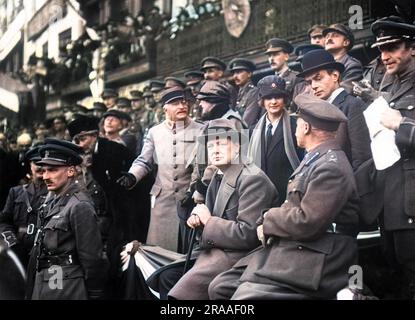 Winston Churchill as a War Office minister, sitting with others on a grandstand at Lille, France, watching the march past of the 47th (2nd London) Division who liberated Lille from German occupation on 17 October 1918, towards the end of the First World War.     Date: 1918 Stock Photo