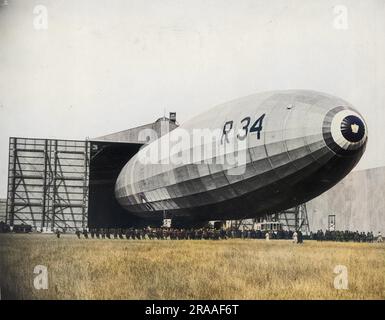 The British R34 (R33 class) airship emerging from her hangar.  She was a rigid airship, built for the RNAS (Royal Naval Air Service) during the First World War.  She made her first flight on 14 March 1919, and was the first aircraft to make an east-west crossing of the Atlantic Ocean, 2-6 July 1919.     Date: circa 1918-1919 Stock Photo