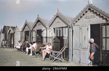 People outside their beach huts at Cayeux-sur-Mer, northern France, on a sunny day.     Date: 1929 Stock Photo