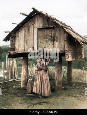 Maori woman outside hut on stilts, New Zealand.     Date: circa 1890s Stock Photo