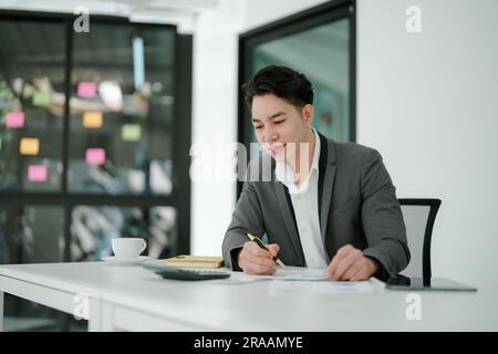 businessman or accountant working on calculator and laptop computer to calculate business data during using accountancy document at office. Stock Photo