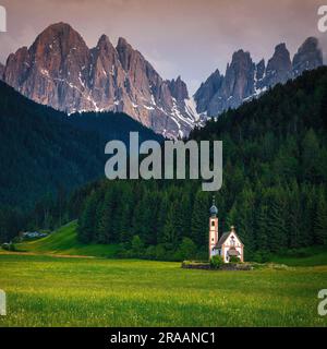 Great travel location, small St Johann church in on the green fields and high mountains at sunset, Funes valley, Santa Maddalena village, Dolomites, I Stock Photo