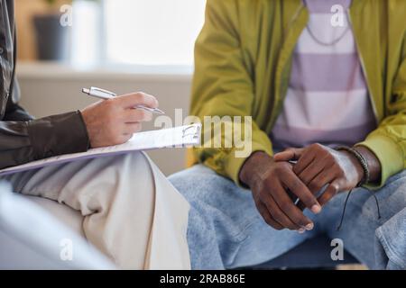Close-up of psychologist making notes and talking to patient during psycho consultation Stock Photo
