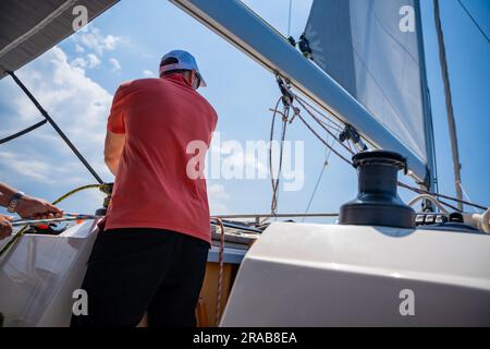 Mans pulling winch rope on sailing boat Stock Photo
