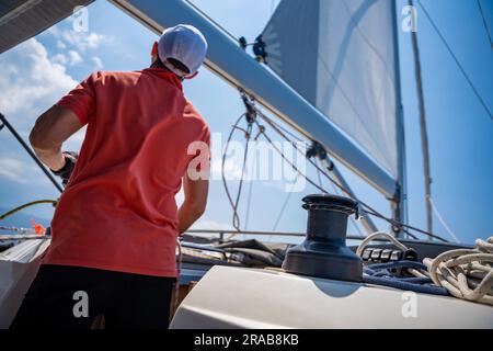 Mans pulling winch rope on sailing boat Stock Photo