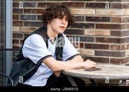 young man sitting at an outdoor cafeteria table Stock Photo