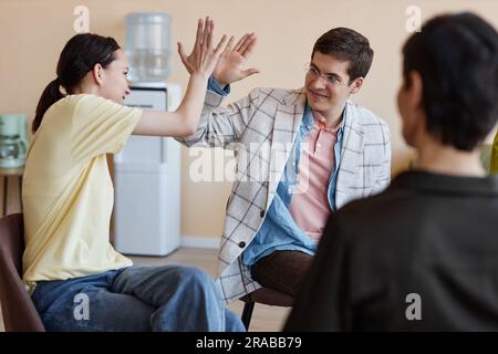Young people greeting each other while sitting together with psychologist at session Stock Photo