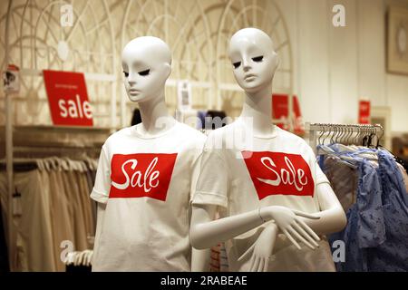 T-shirts with Sale inscription on mannequins in clothing store. Different summer clothes for men and women Stock Photo
