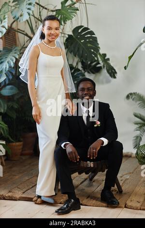 Full length wedding portrait of black young couple as bride and groom posing together in orangerie Stock Photo