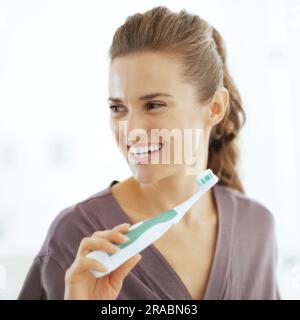 Happy young woman brushing teeth in bathroom Stock Photo