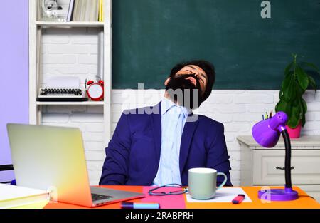 Sleeping male student in classroom. Tired overworked teacher sleep at desk. Knowledge and educational school concept. Teacher or student preparing for Stock Photo